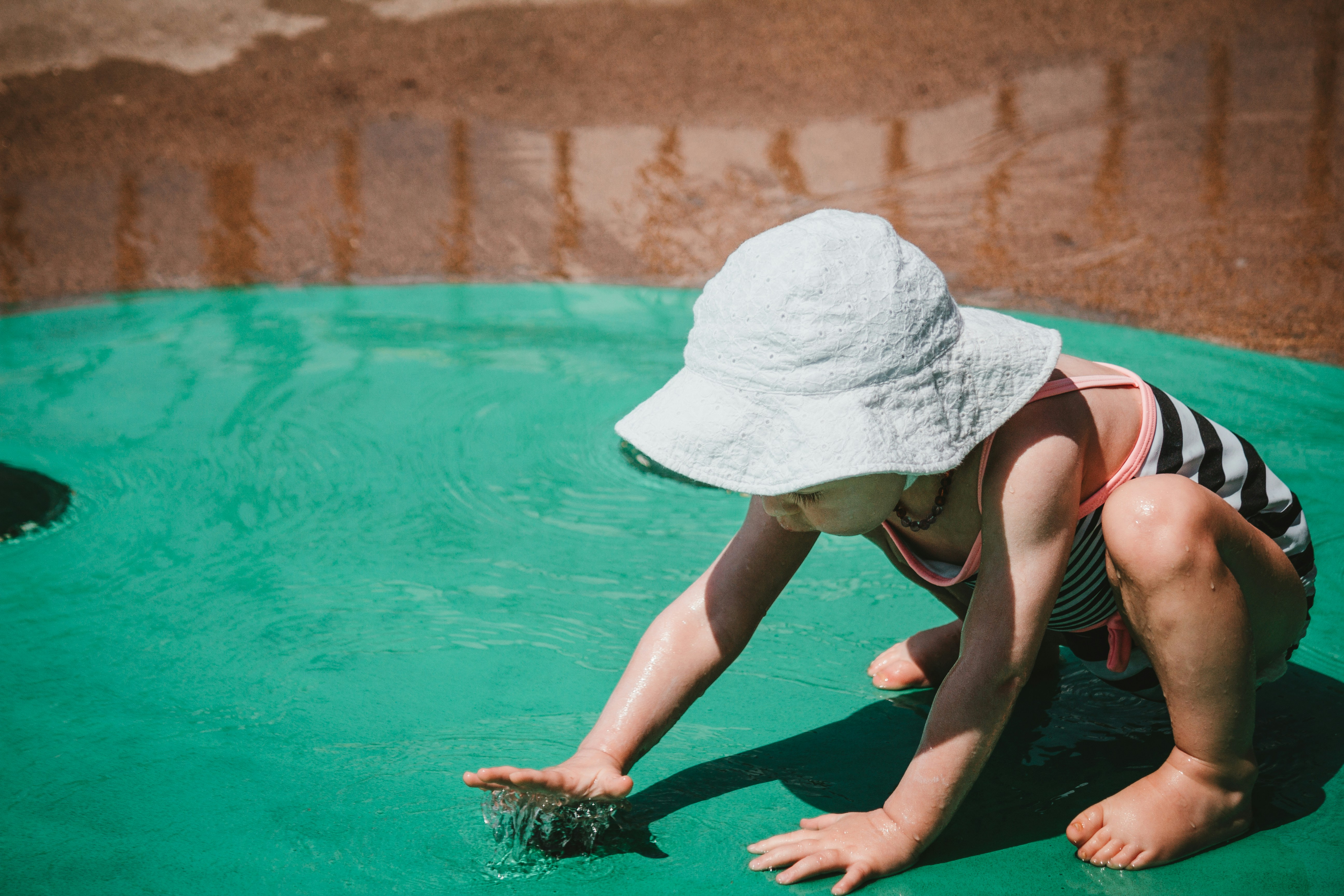 a young child playing in a pool of water, Summer time fun.