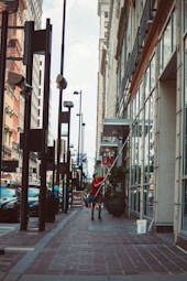 a woman walking down a sidewalk next to tall buildings