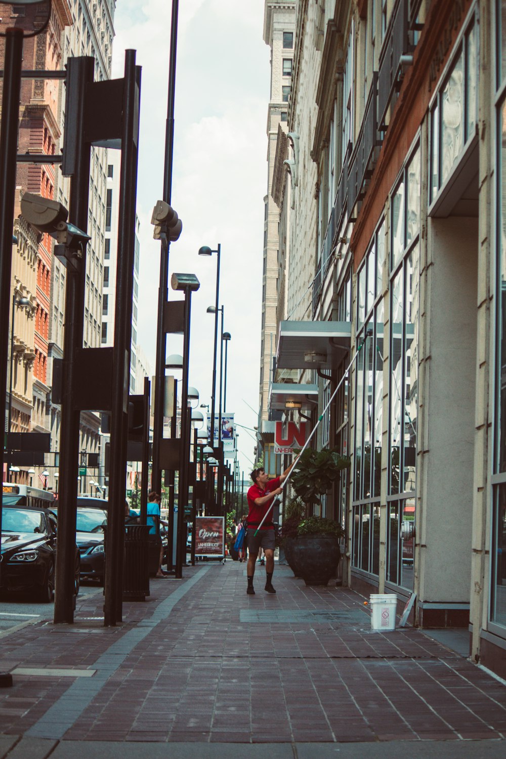 a woman walking down a sidewalk next to tall buildings