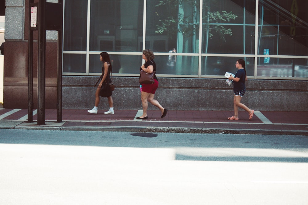 a group of people walking down a street next to a tall building