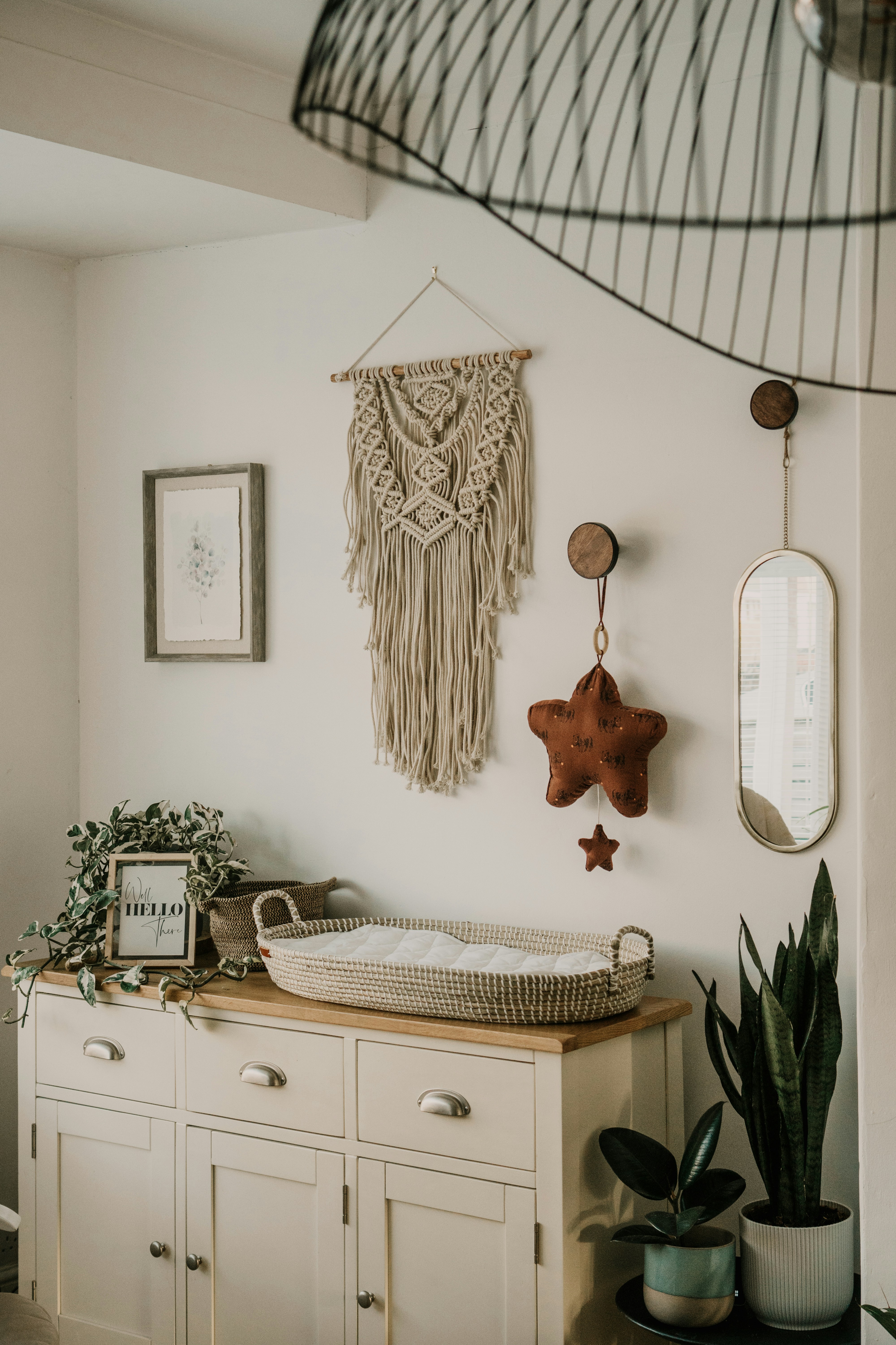 a bedroom with a white wooden desk in a room with macrame hanging on the wall and plants