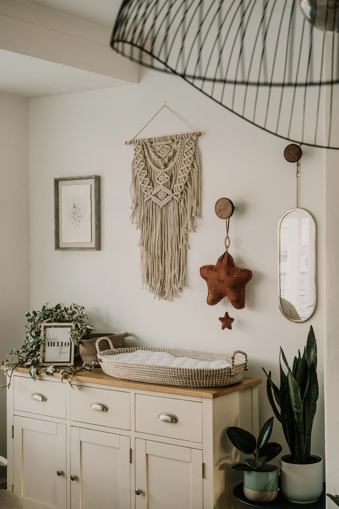 Quarto decorado com painel de macramê na parede, plantas e móveis de madeira