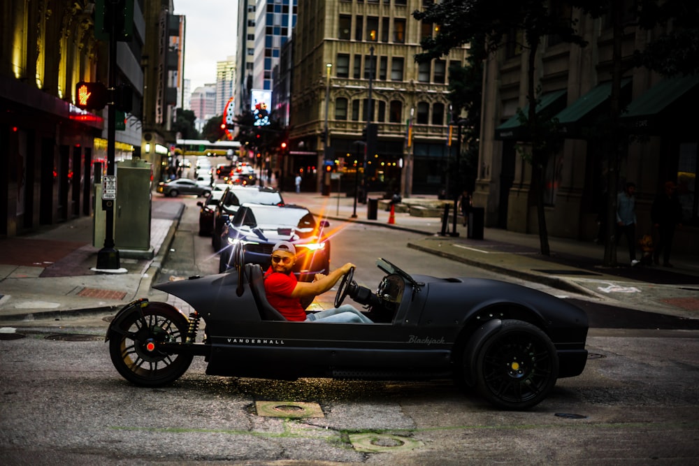 a man driving a car down a street next to tall buildings