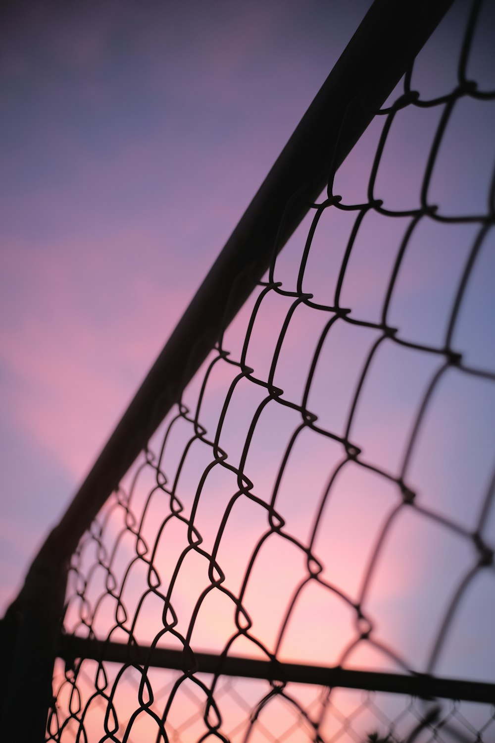 a chain link fence with a sunset in the background