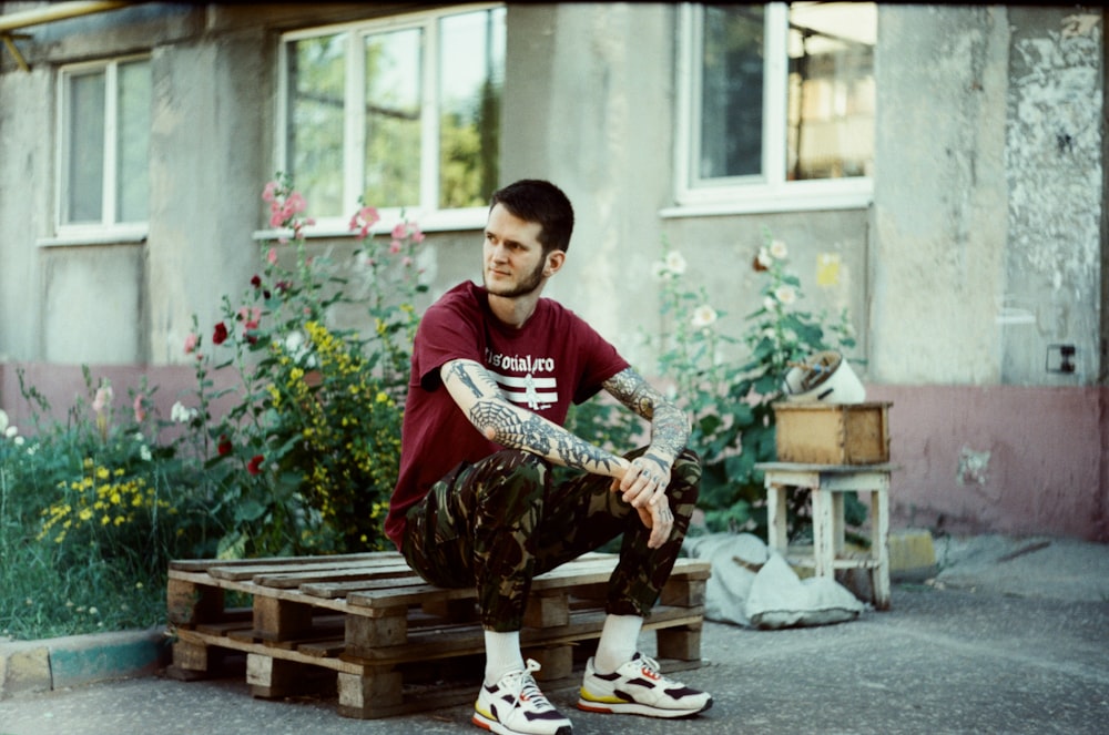 a man sitting on a wooden bench in front of a building