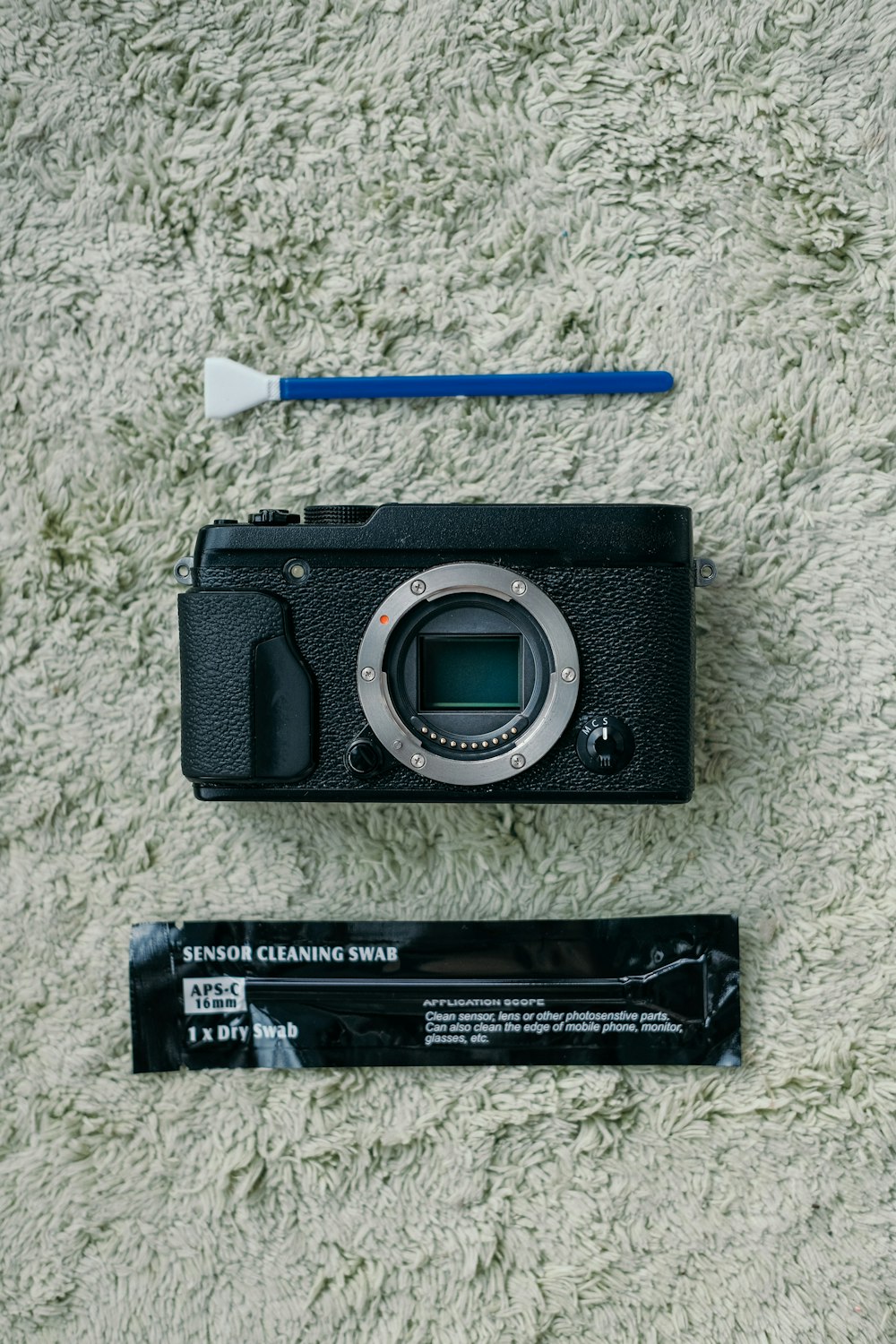 a camera sitting on top of a carpet next to a battery