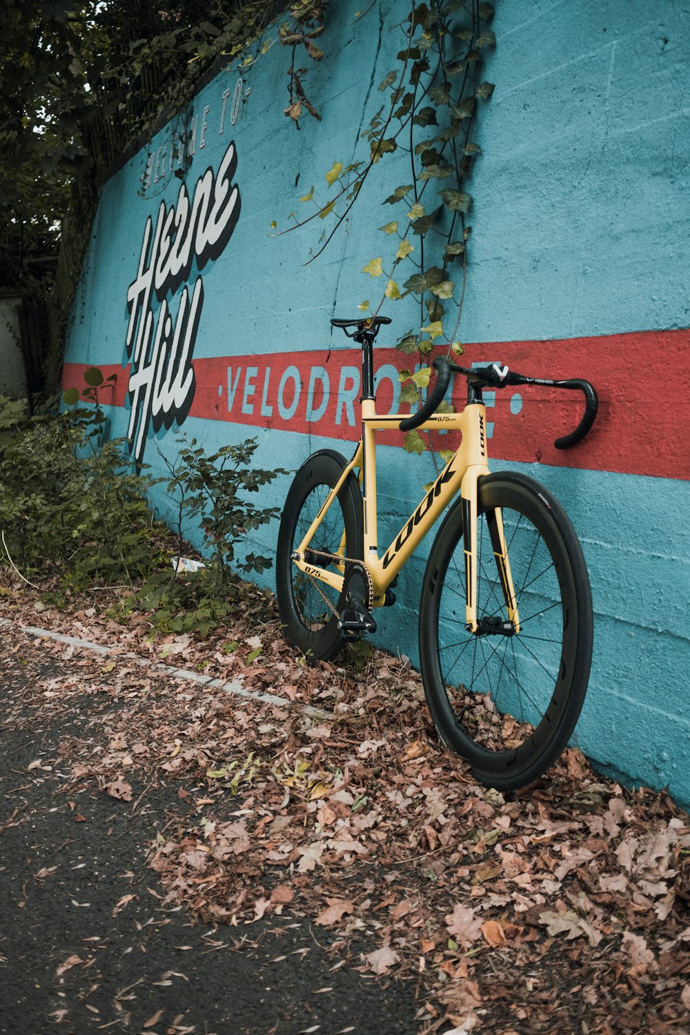 a yellow bicycle leaning against a blue wall