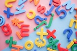 a pile of plastic letters and numbers on a pink and blue background