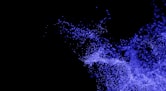 a black background with blue powder flying in the air