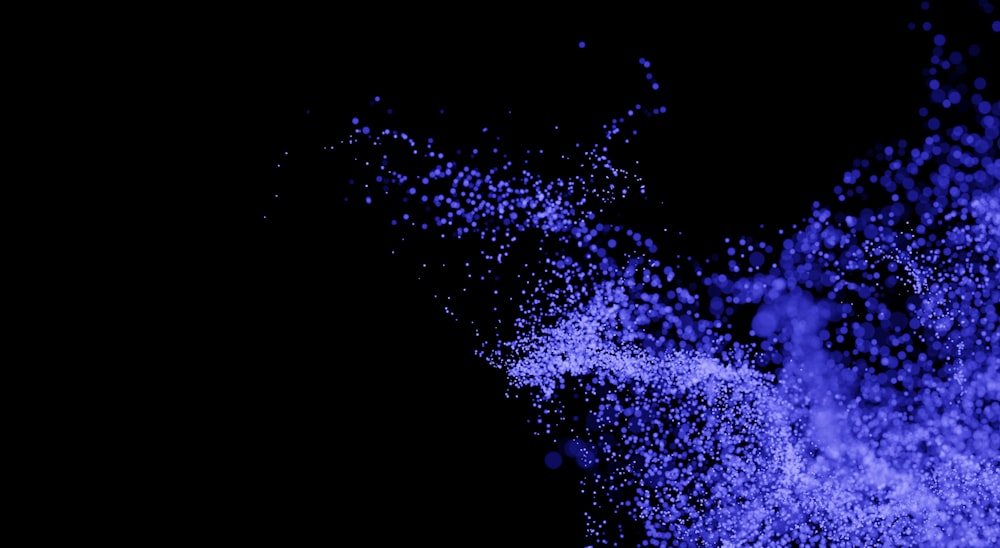 a black background with blue powder flying in the air