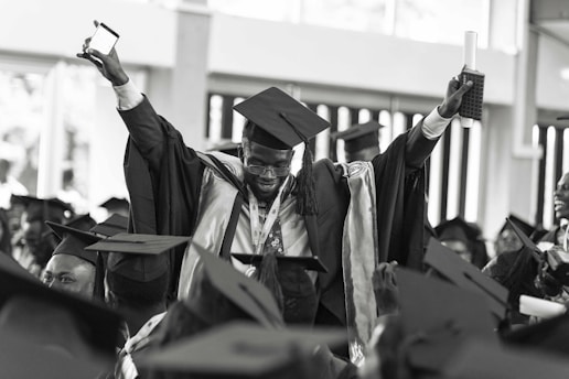 Graduates celebrating on stage with bright lights and joyful expressions