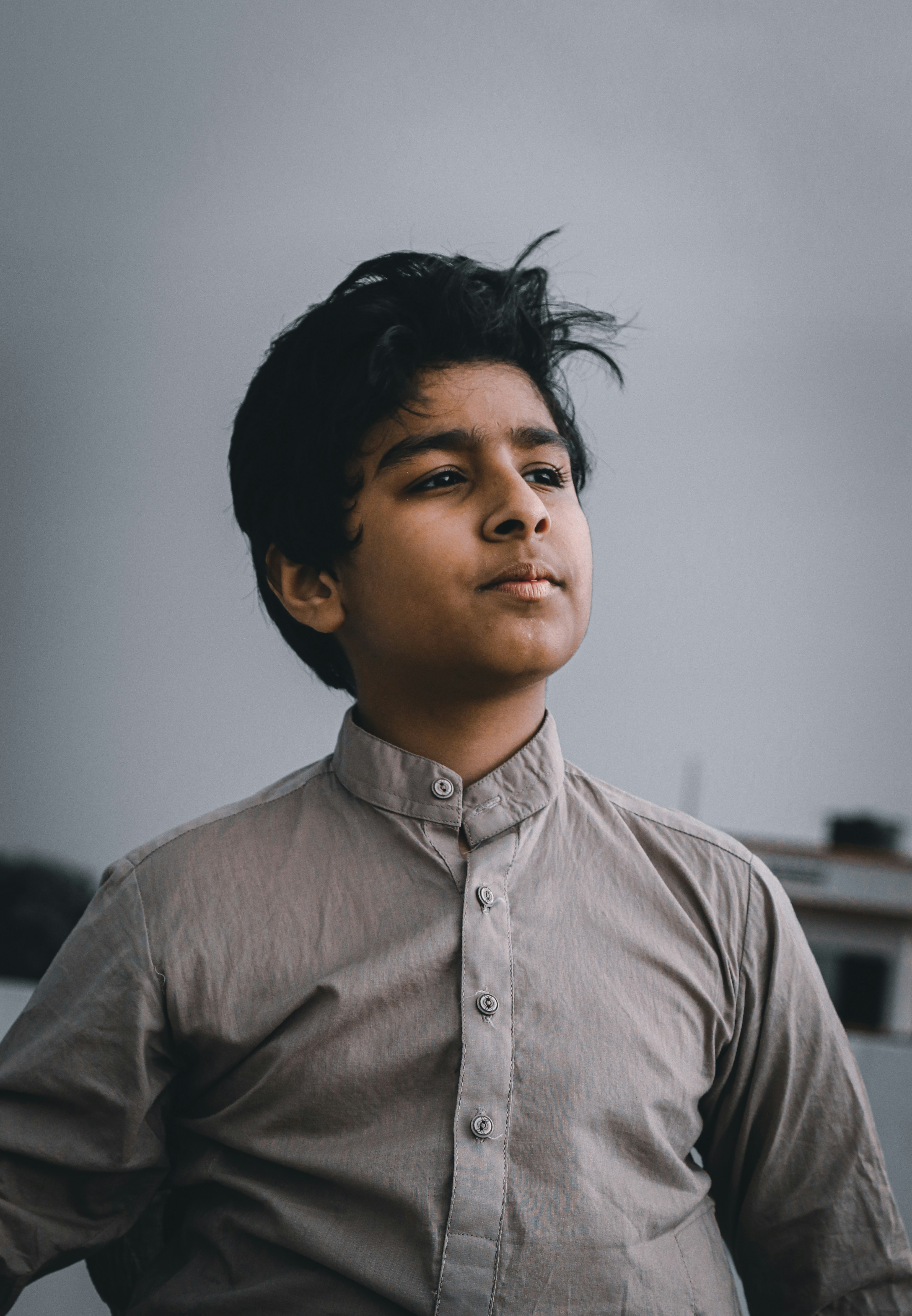 Foto zum Thema Ein junger Mann mit schwarzen Haaren steht vor einem Gebäude Kostenloses Bild