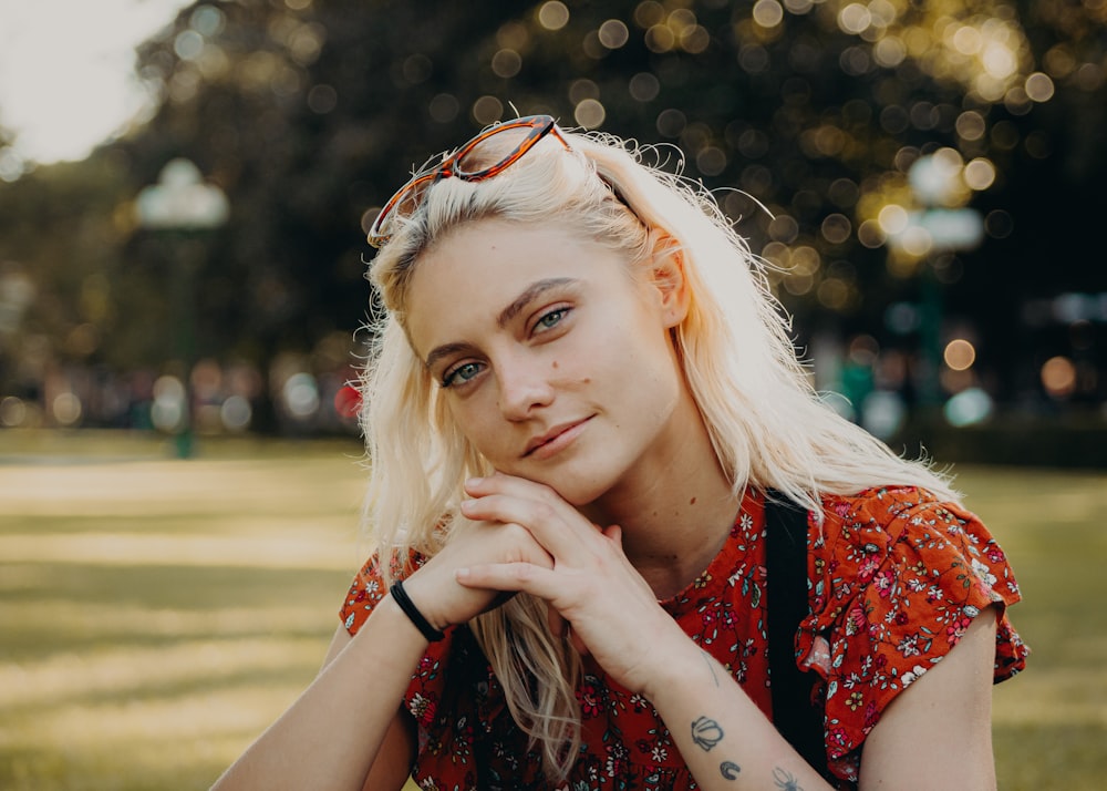 a woman sitting on the grass with her hand on her chin