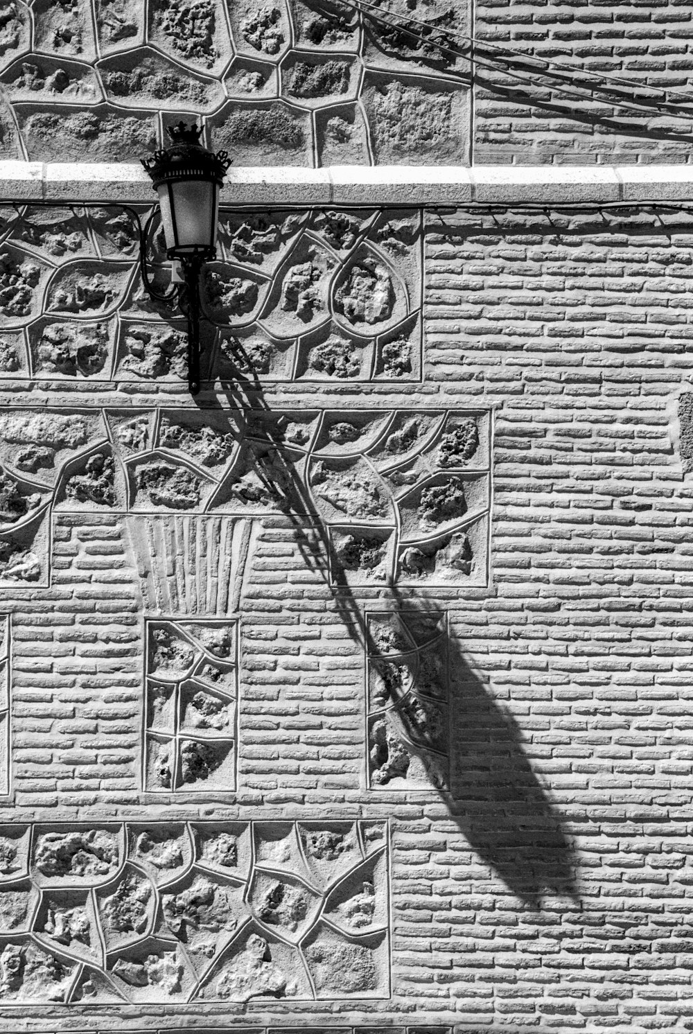 a black and white photo of a street light on a brick wall