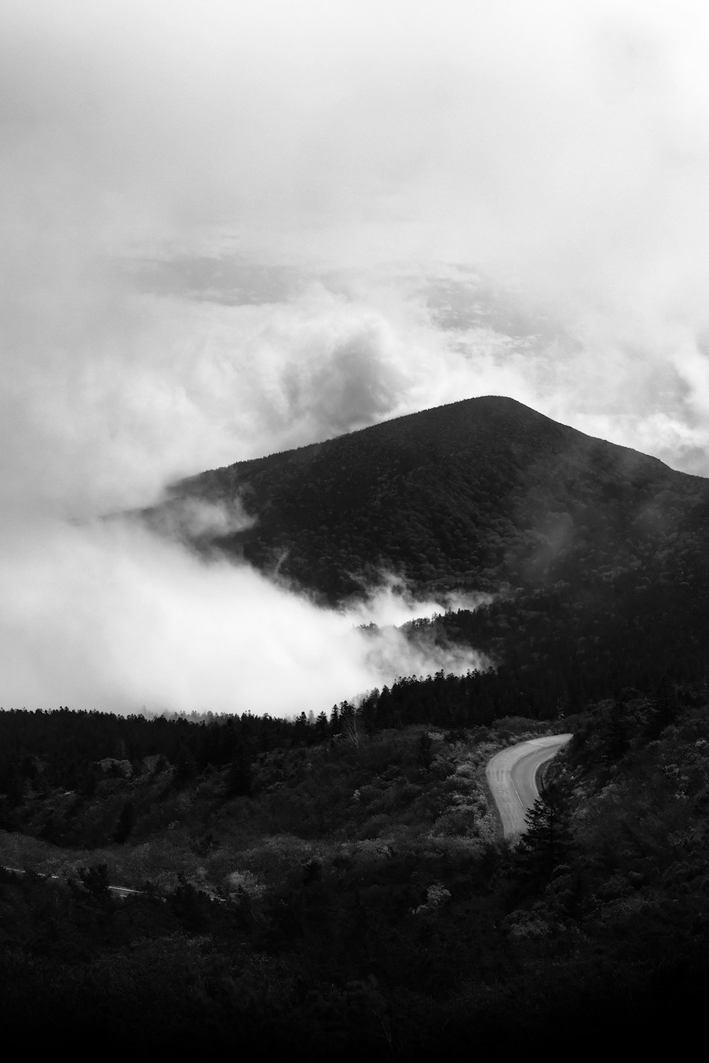 a black and white photo of a road in the mountains