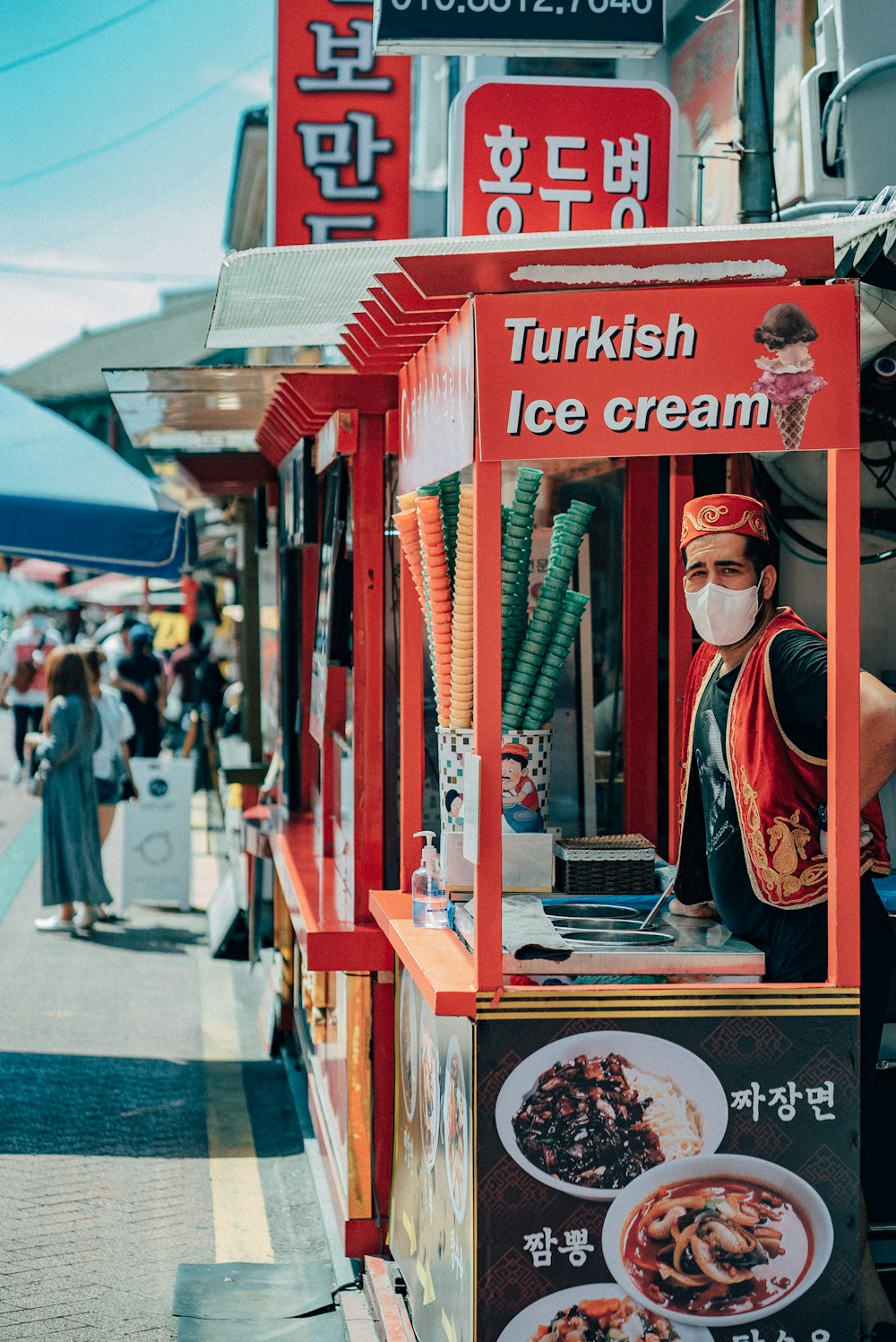 a man wearing a face mask standing in front of a food stand