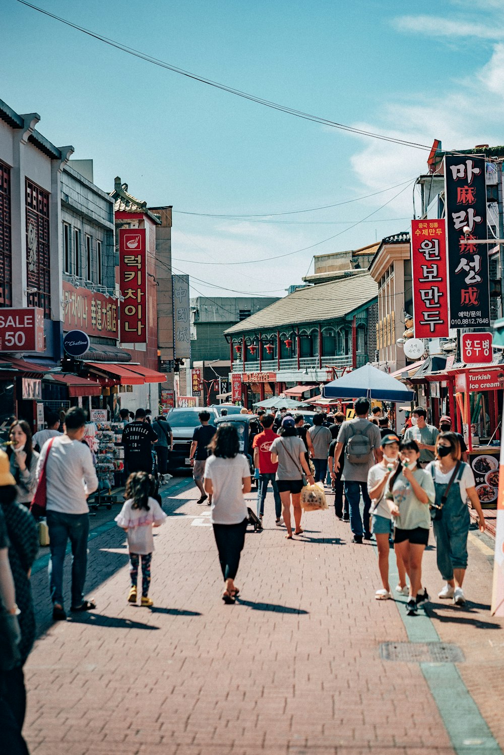 a crowd of people walking down a street next to tall buildings