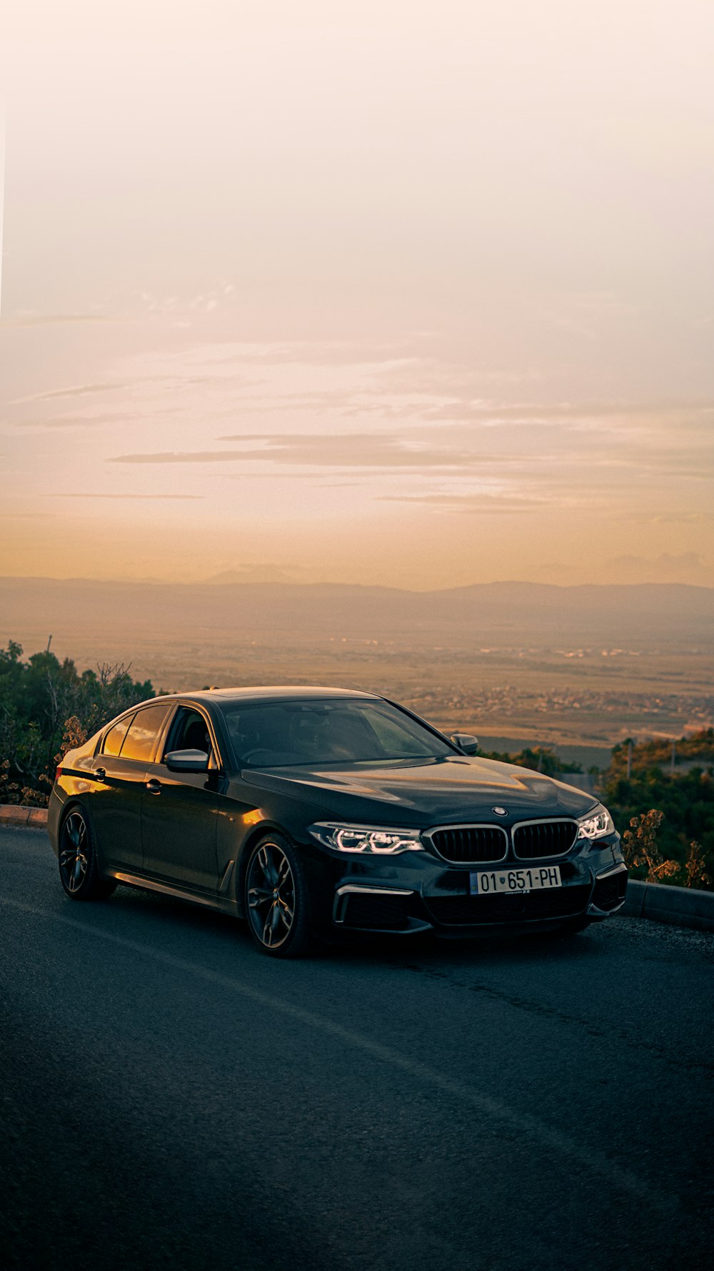 a black car driving down a road next to a forest