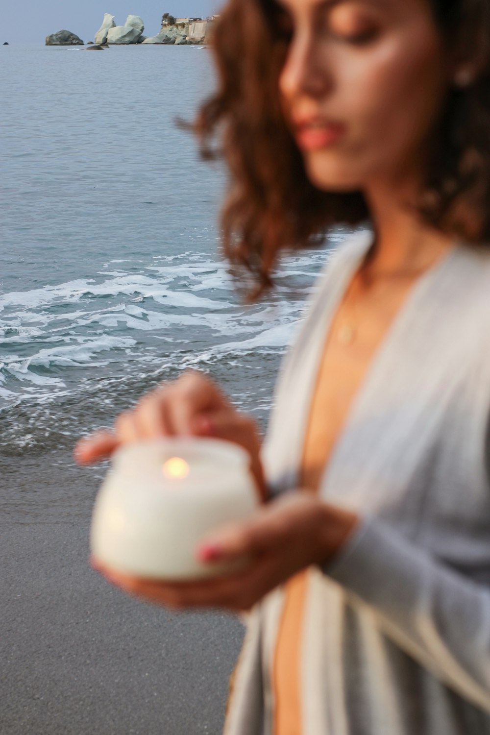 a woman standing on a beach holding a coconut