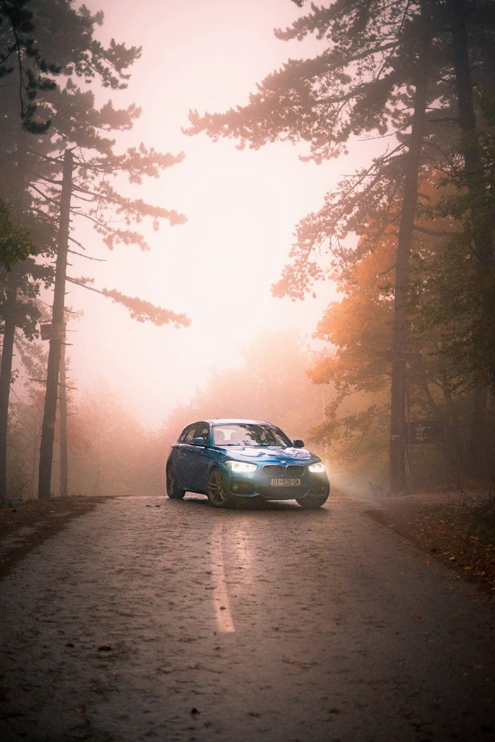 a blue car driving down a foggy road