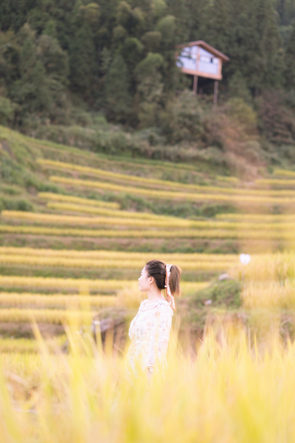 a woman standing in a field with a house in the background