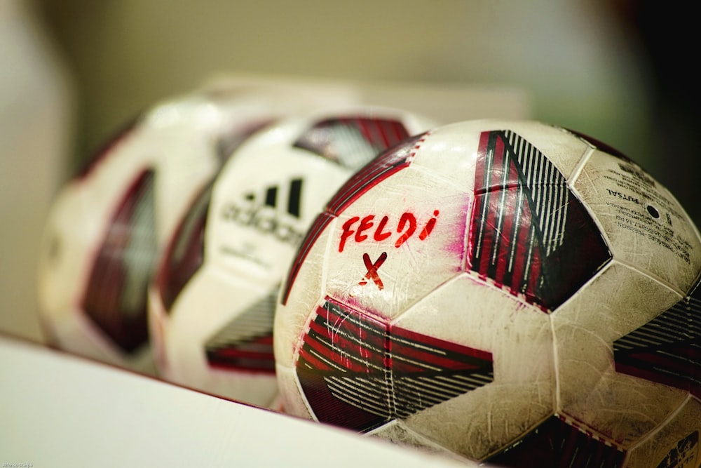 a close up of three soccer balls on a shelf