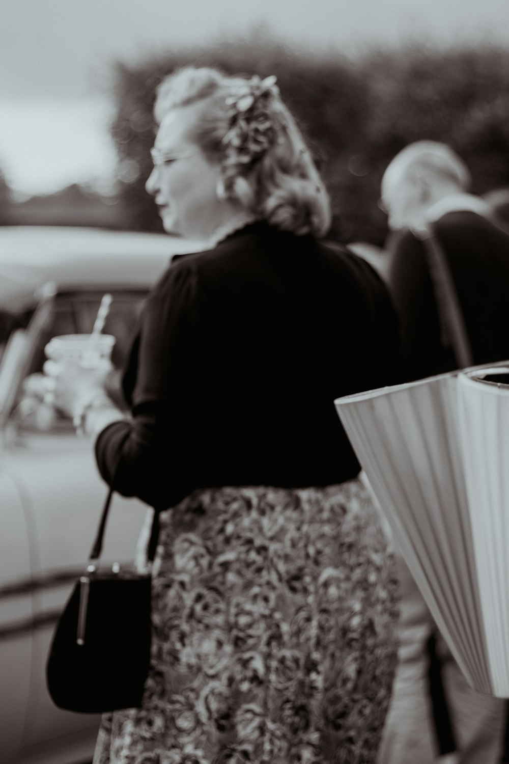 a woman walking down a street holding a drink