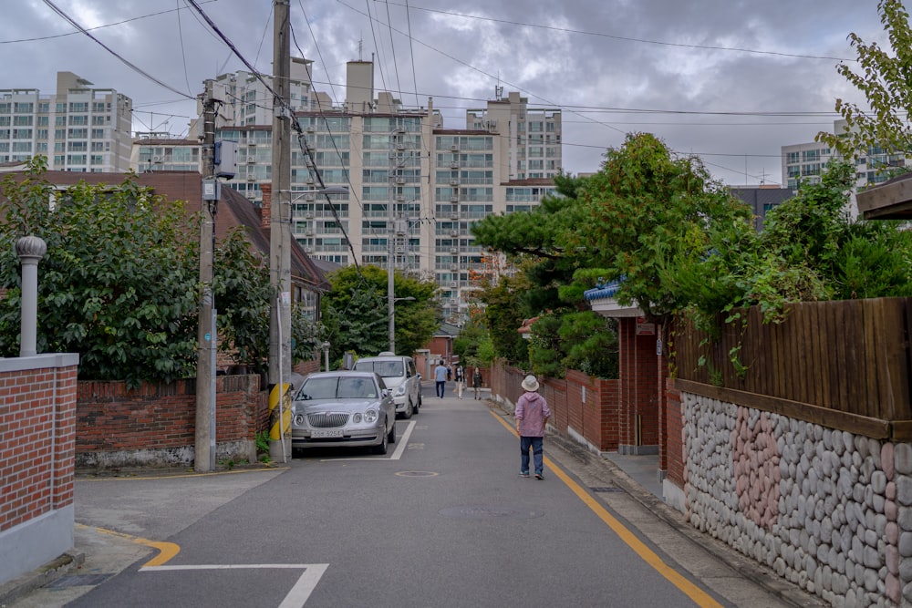 a woman walking down a street next to tall buildings