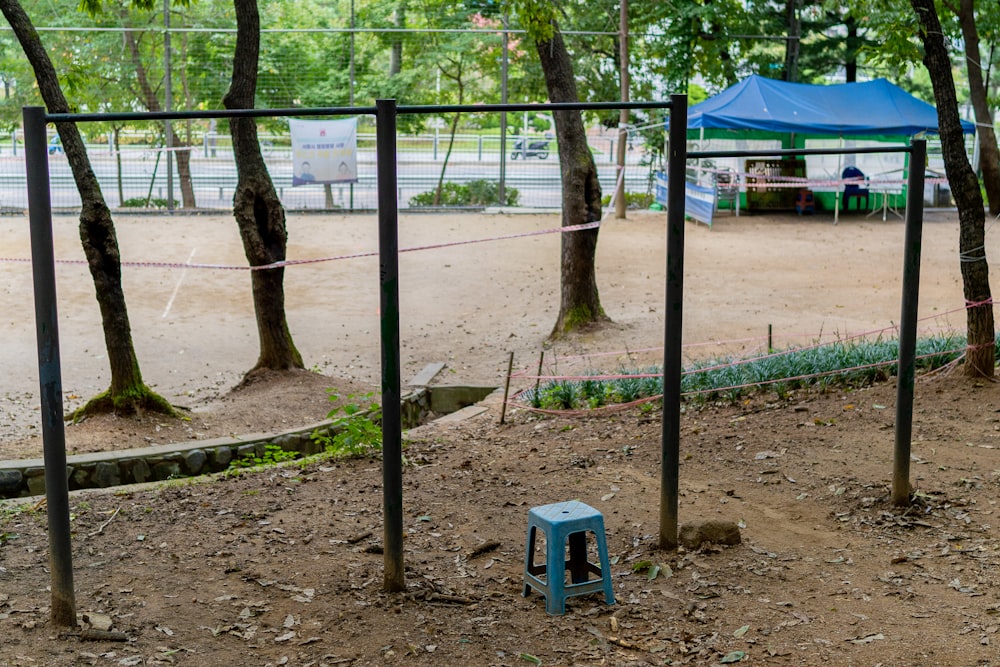 a blue stool sitting on top of a dirt field