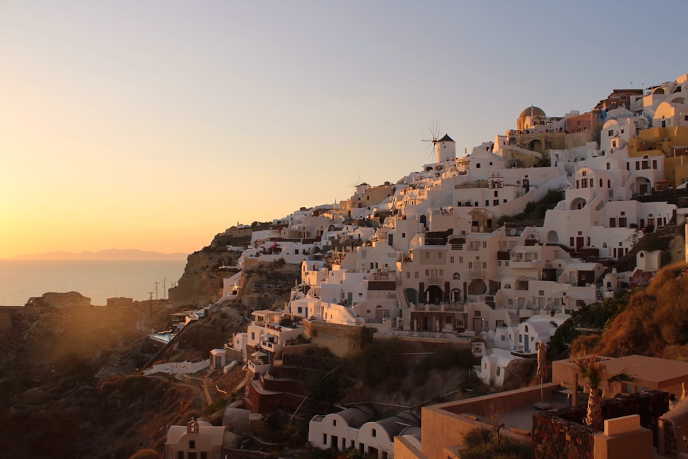 the sun is setting on a hillside with houses on it