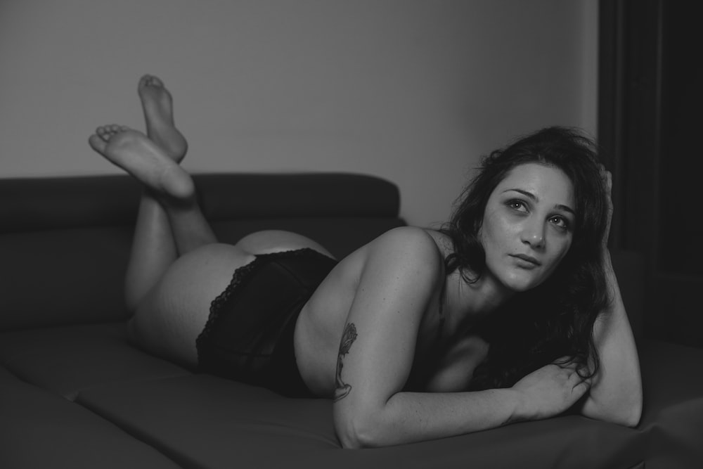 a black and white photo of a woman laying on a couch