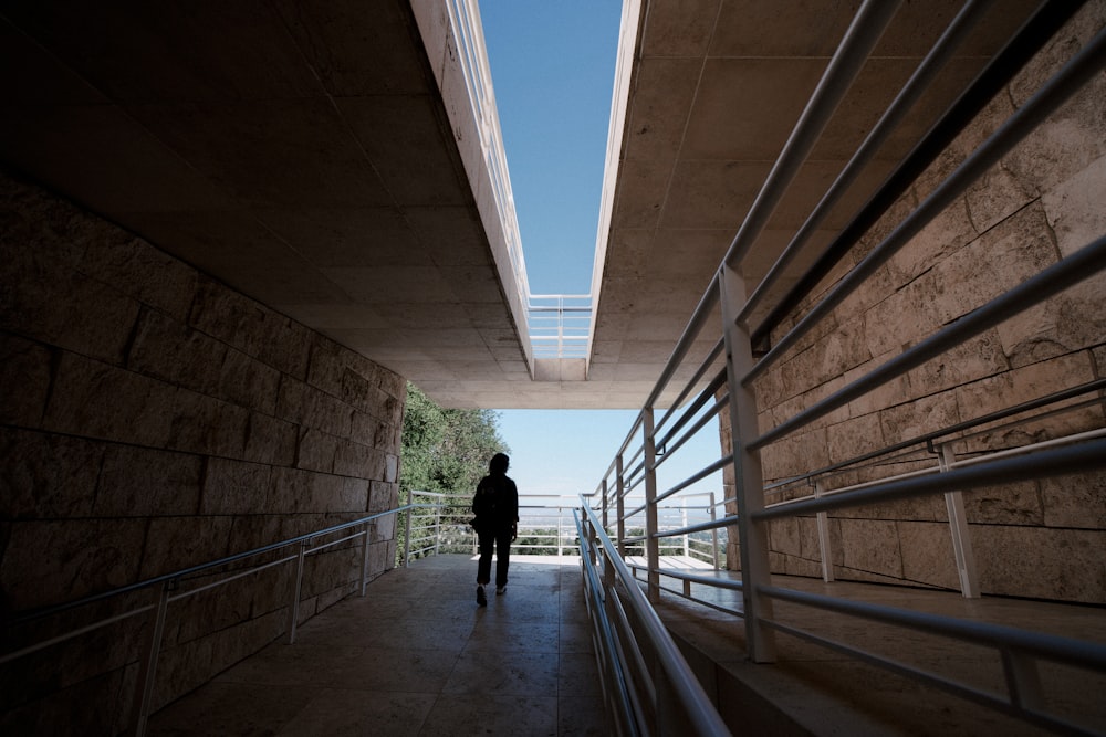 a person walking down a walkway under a bridge