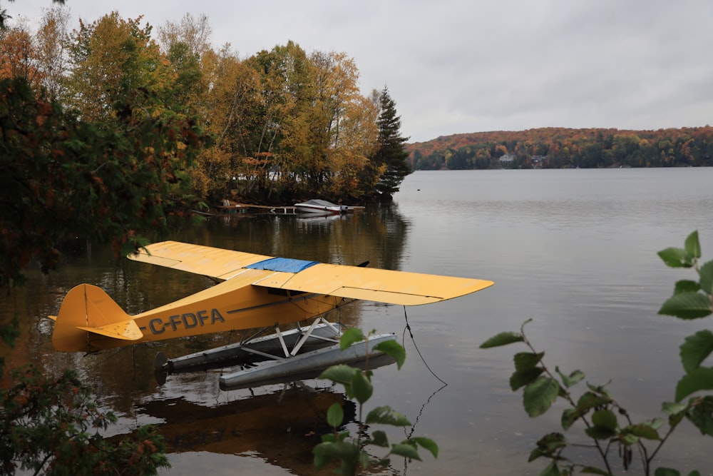 a small yellow plane sitting on top of a lake