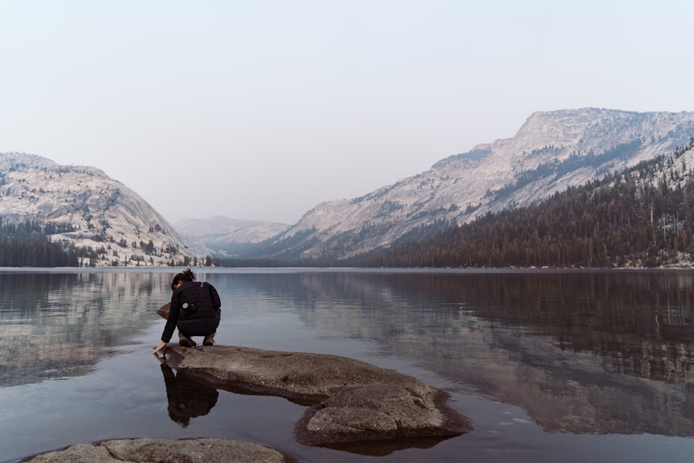 a person sitting on a rock near a body of water