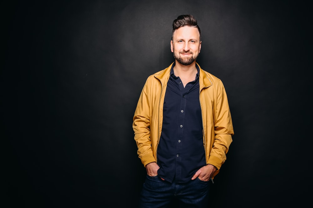 a man standing in a dark room with his hands in his pockets