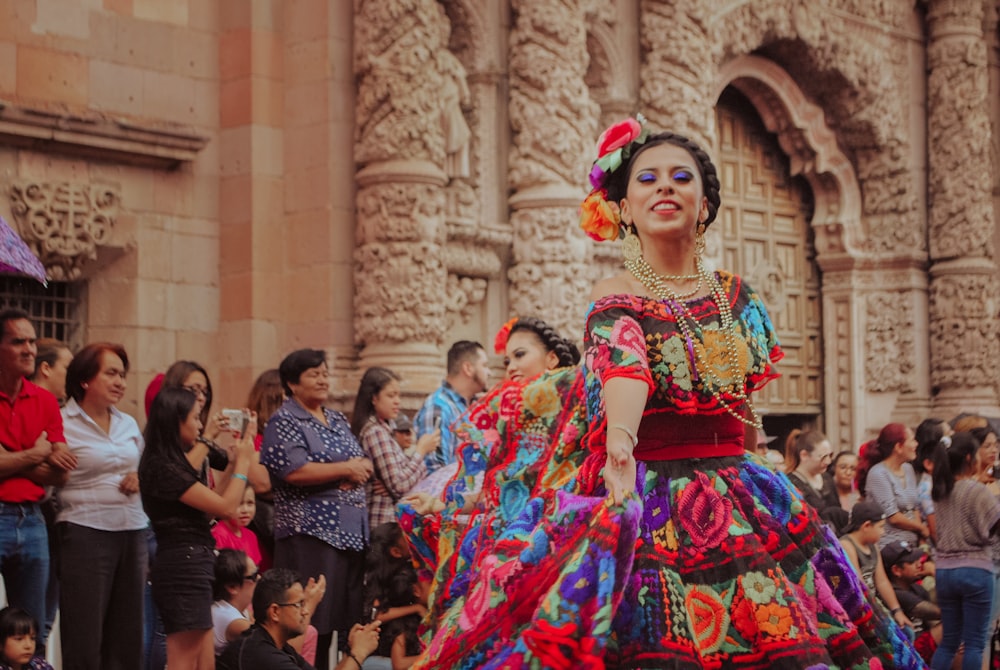 Una mujer con un vestido colorido bailando frente a una multitud