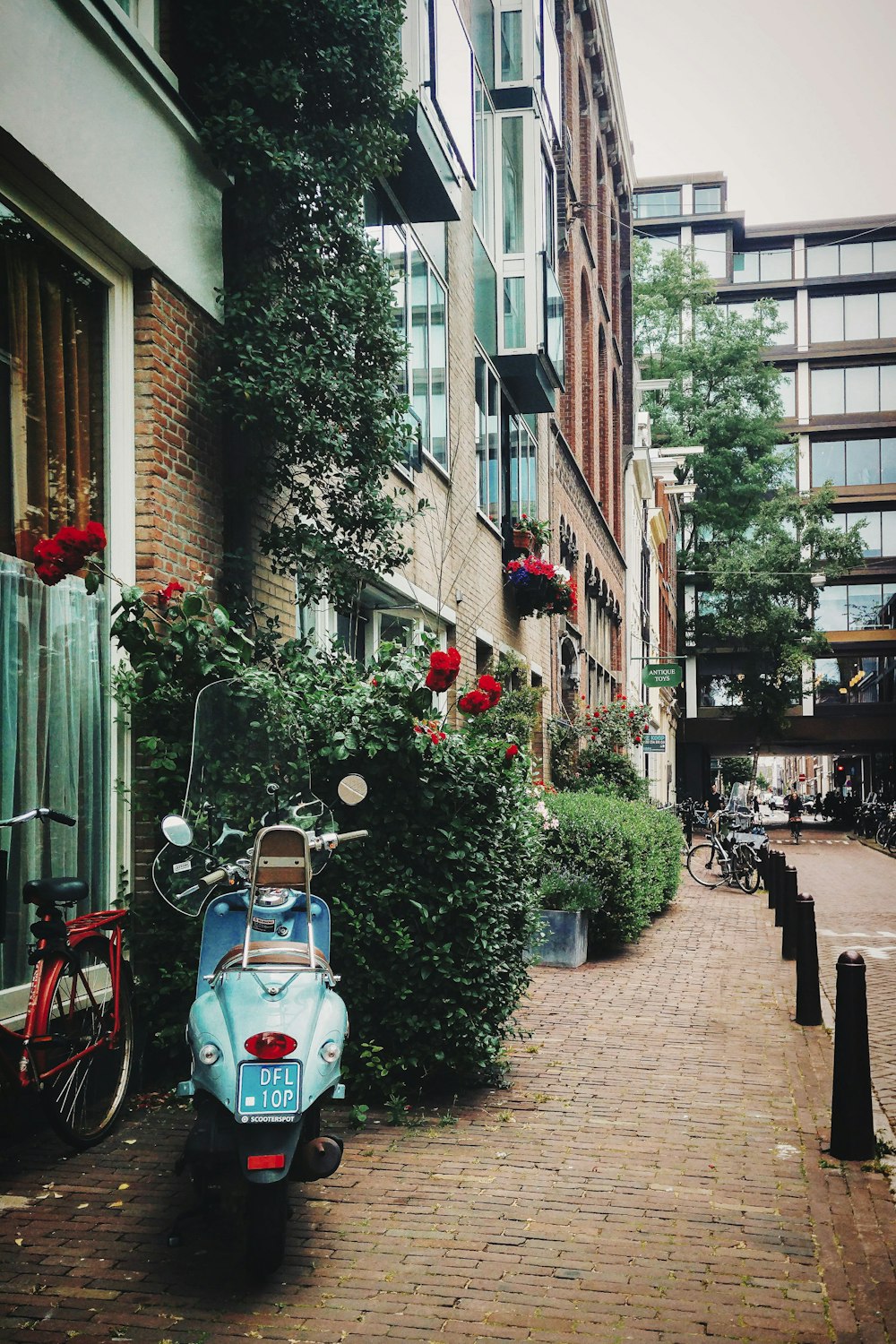 un scooter garé sur un trottoir en briques à côté d’un immeuble