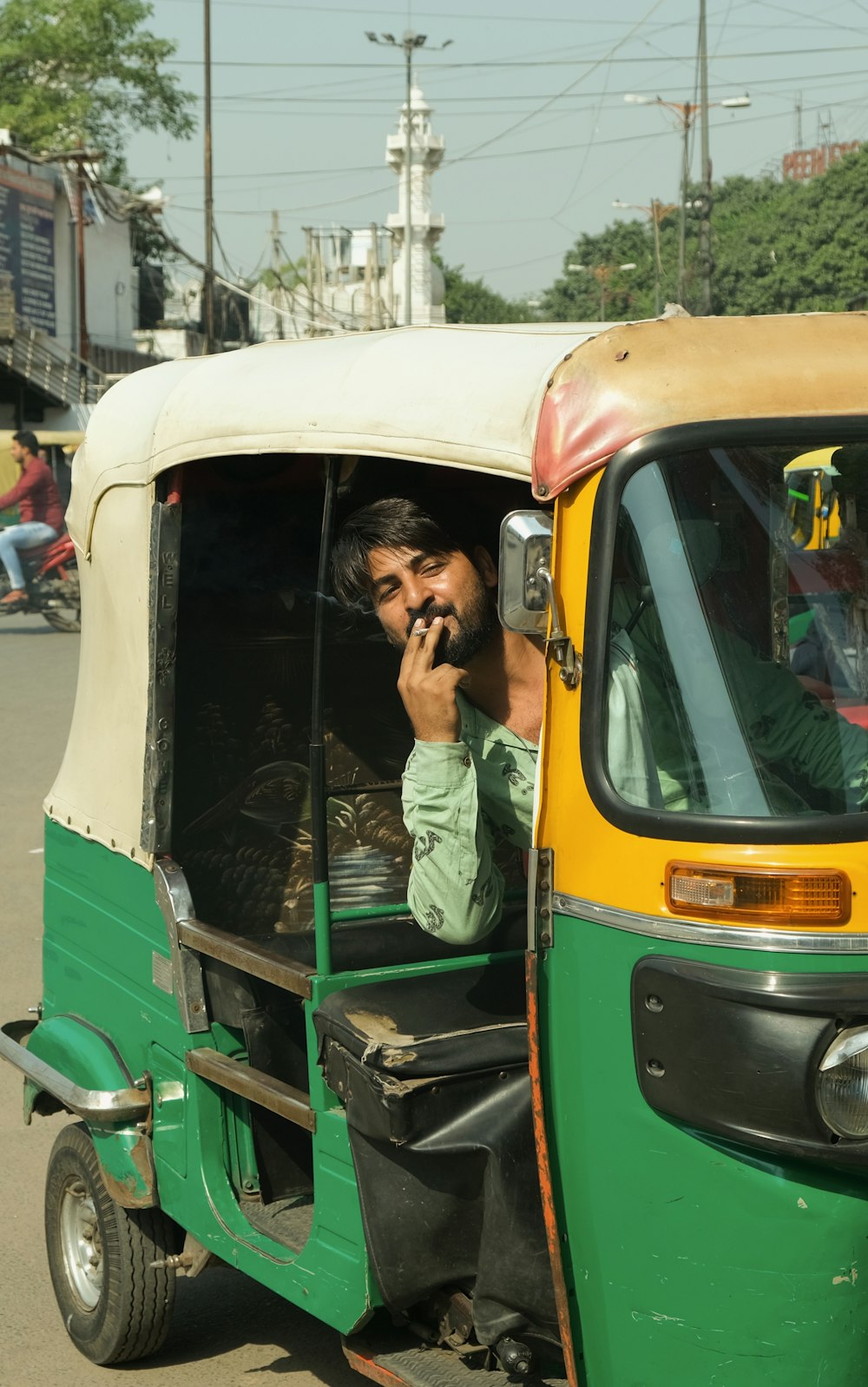a man talking on a cell phone while driving a tuk tuk
