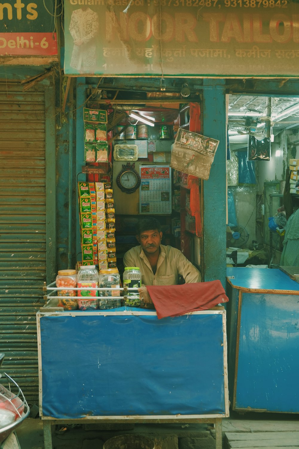 a man sitting at a food stand in front of a store