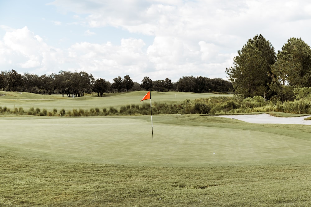 a golf course with a red flag on the green