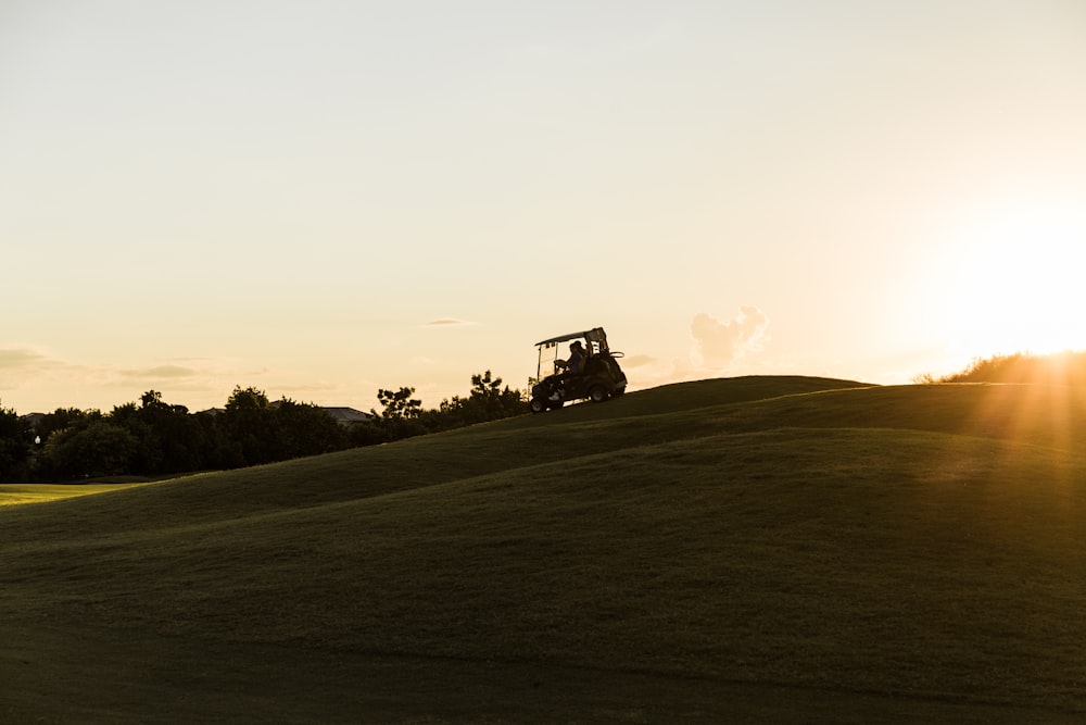 a golf cart driving up a hill at sunset