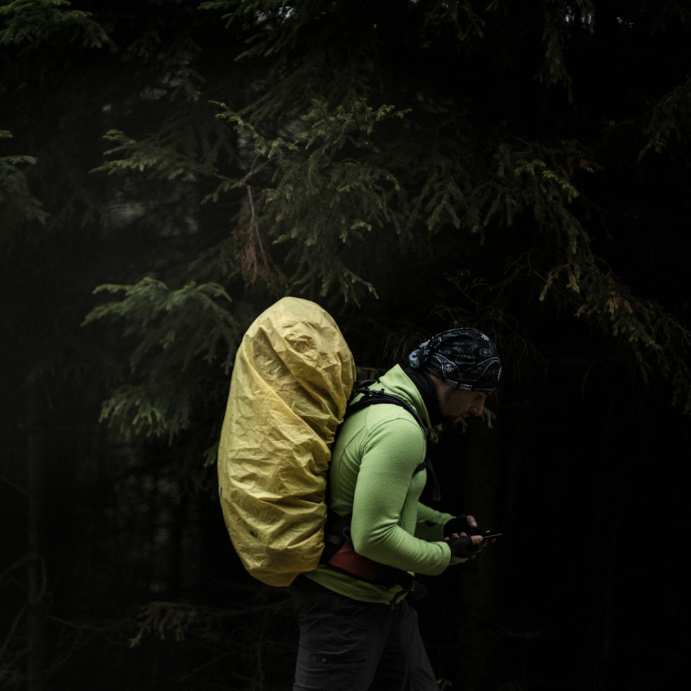 a man with a backpack and raincoat on walking through the woods