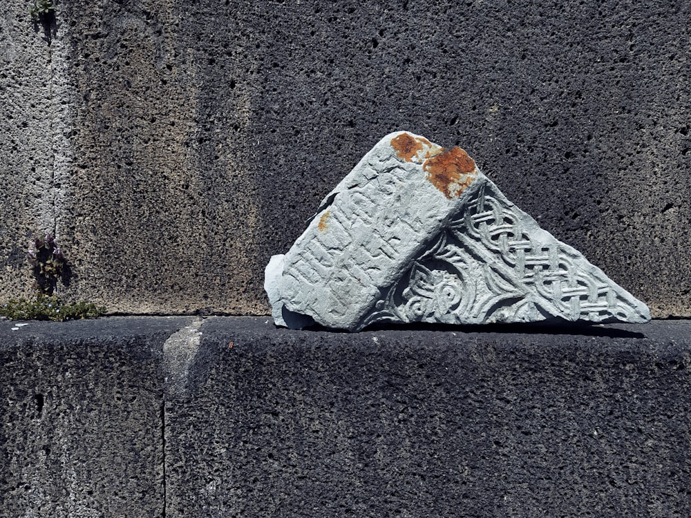 a piece of art sitting on top of a cement wall