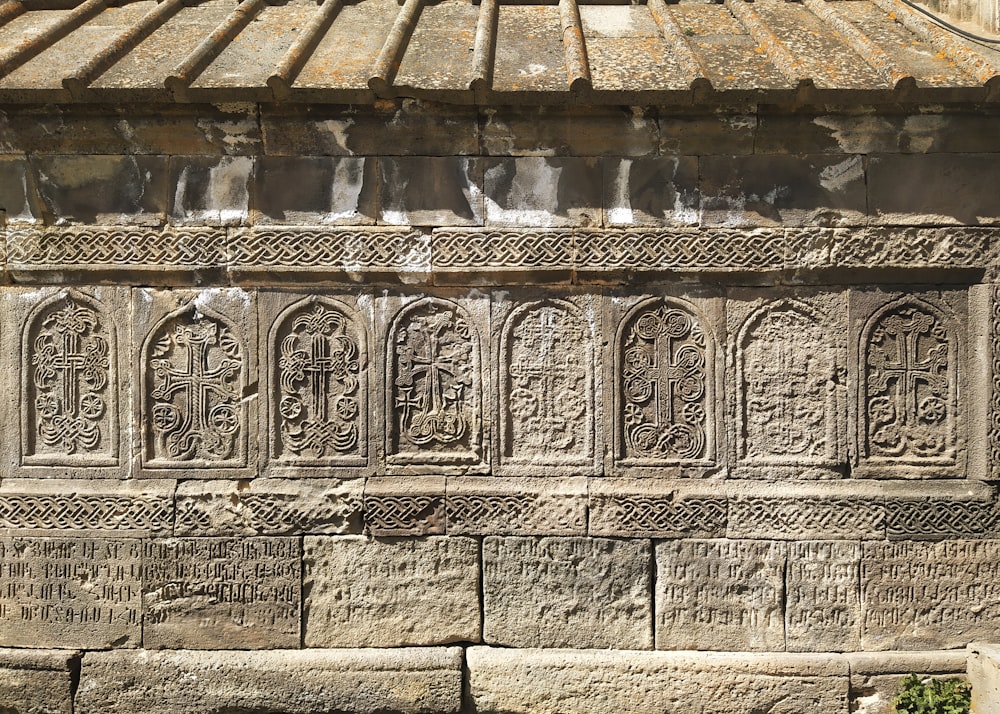 a stone wall with a bunch of carvings on it
