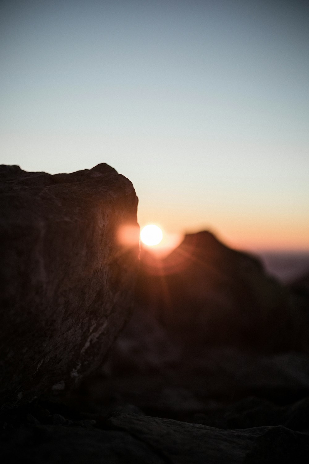 the sun is setting over a rocky outcropping