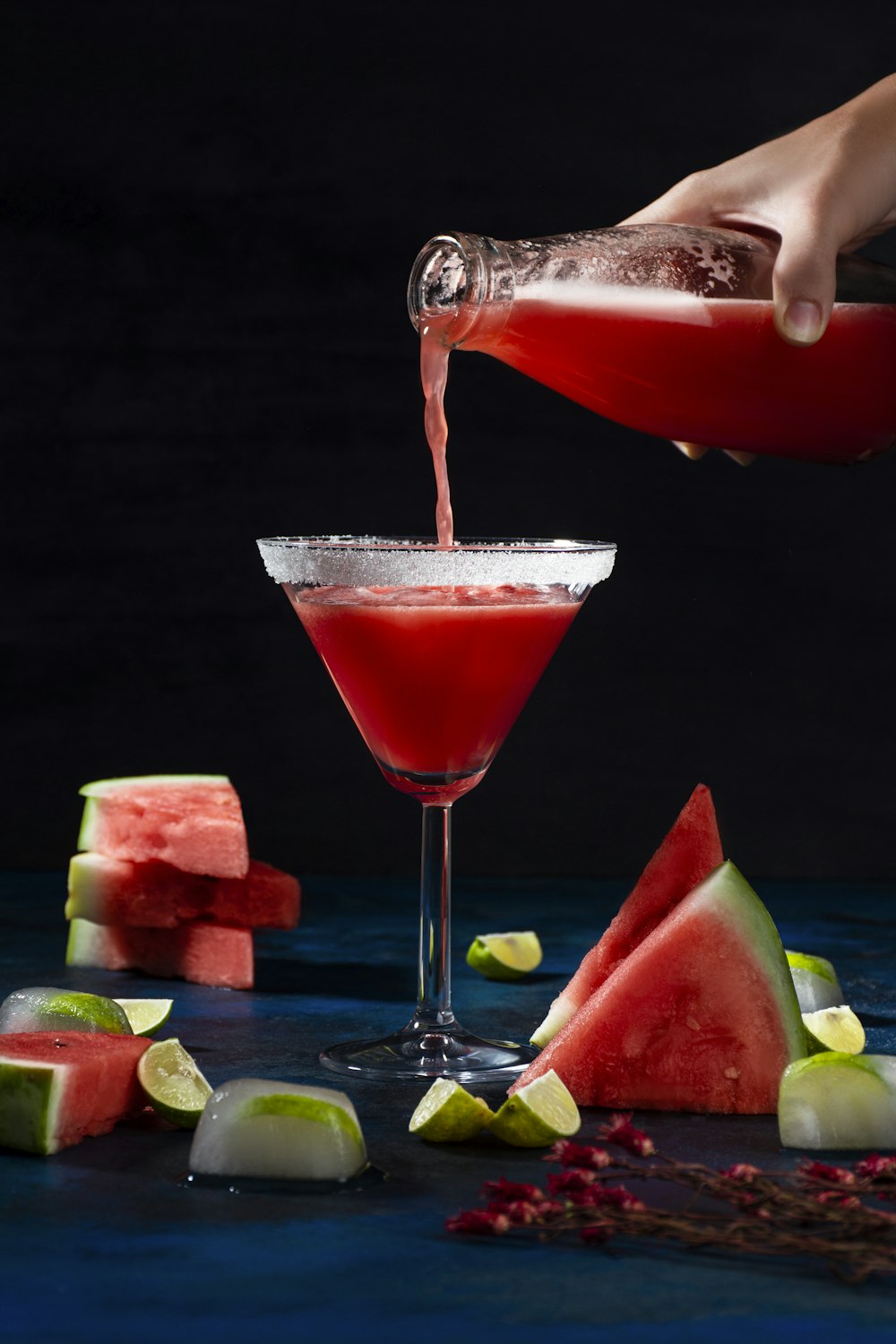 a person pouring a drink into a martini glass