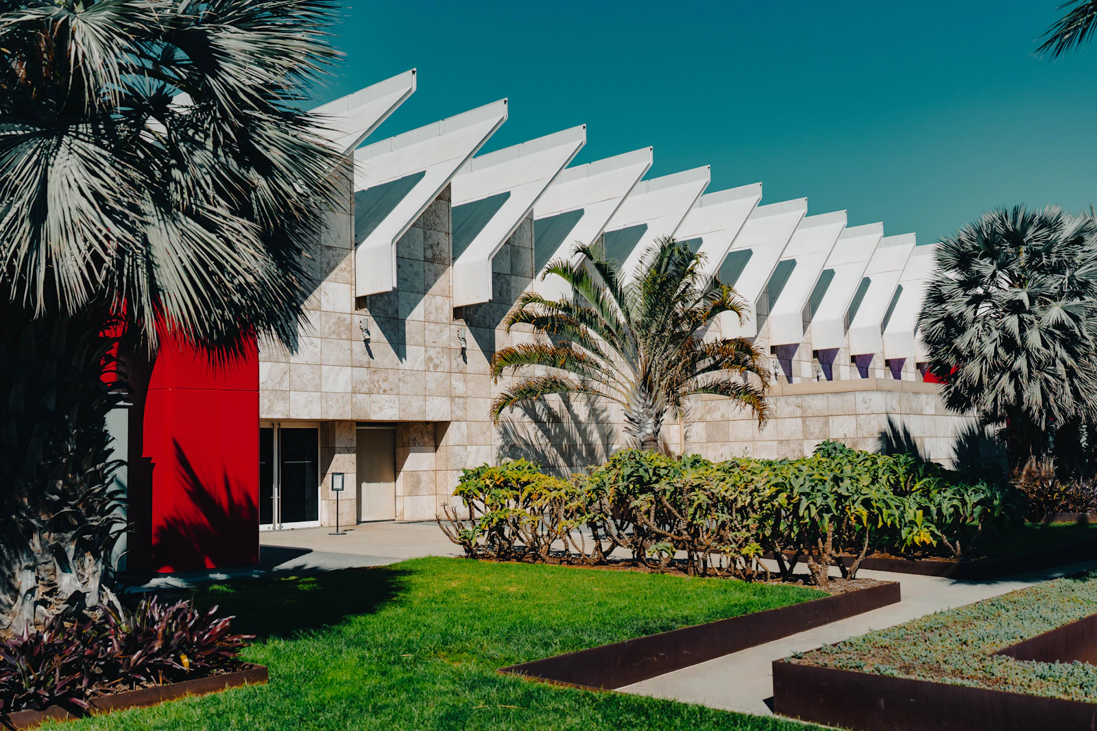 a building with a red door and palm trees in front of it