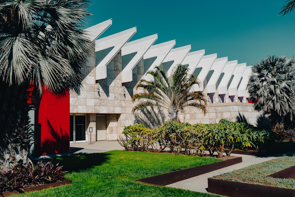 a building with a red door and palm trees in front of it