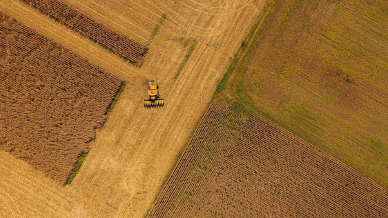 Aerial view of vast Brazilian farmland with modern agricultural machinery working under a clear sky.