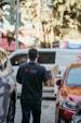 a man walking down a street next to parked cars